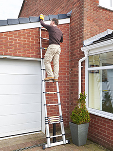 Мужчина ремонтирует крышу телескопической лестницей